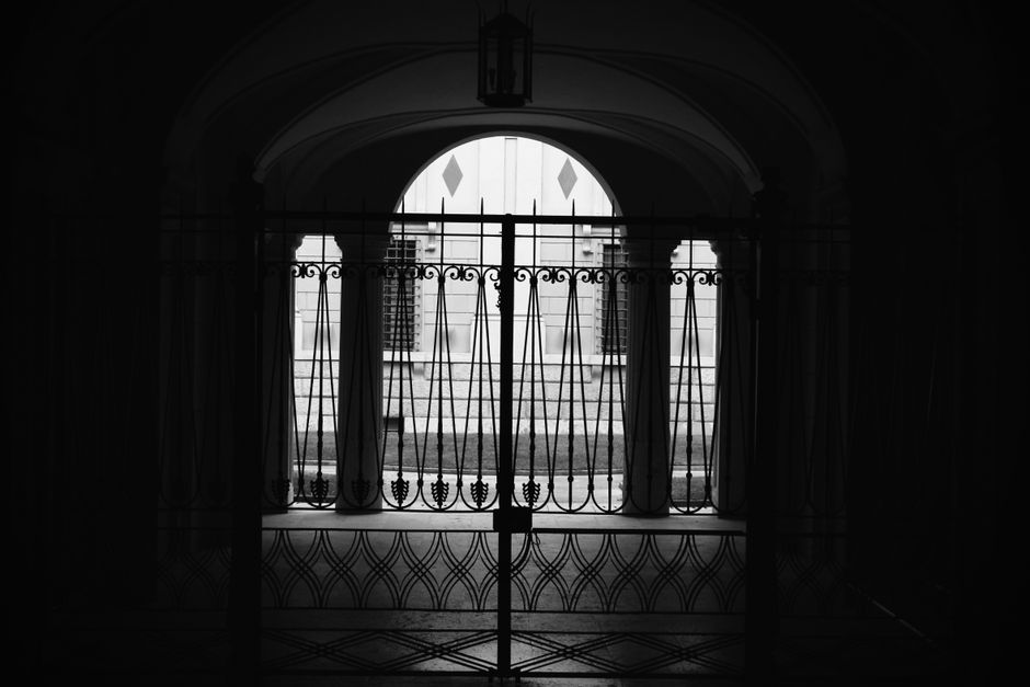 Black and white silhouette of an iron gate with an arched opening.