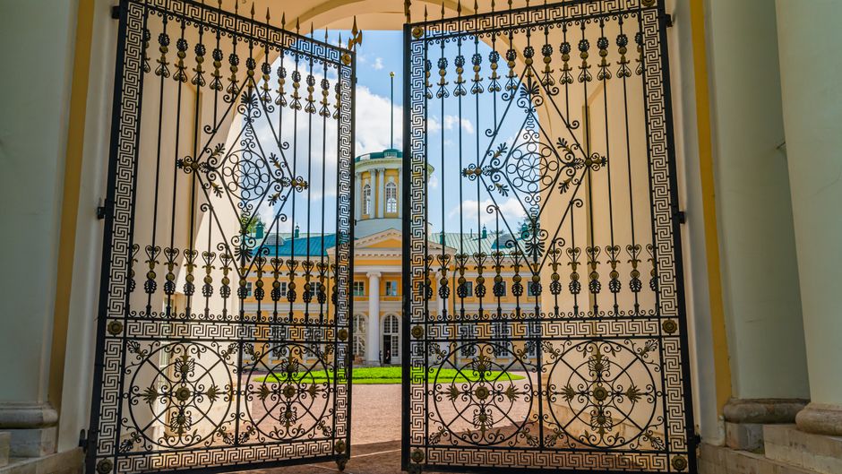 Wrought iron gates standing open on a clear day.