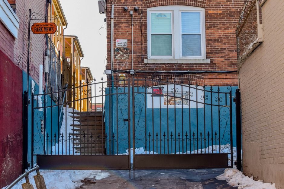 A wrought iron gate beside a brick building.