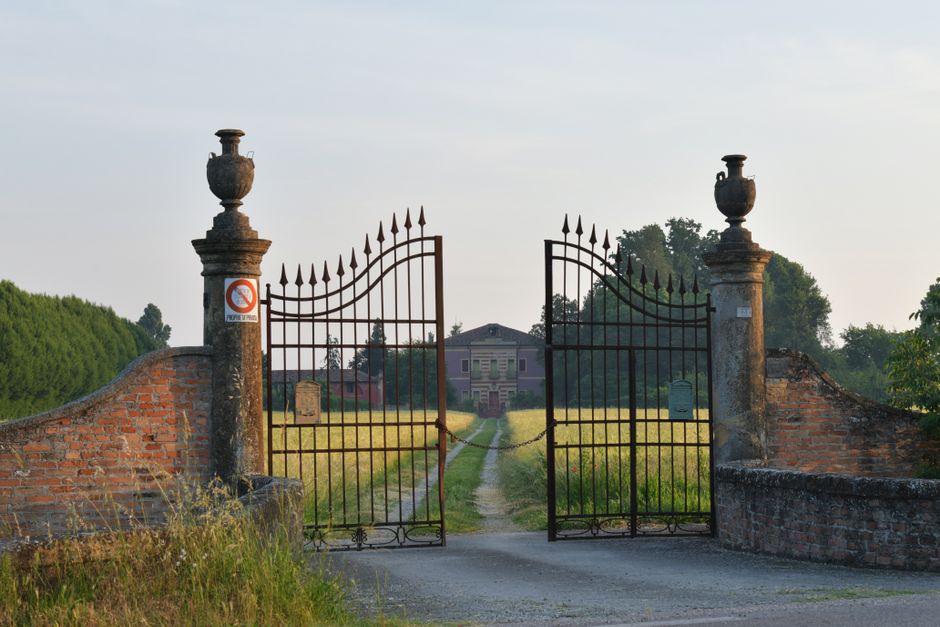 Wrought iron gate opening onto a garden path on a summer day.